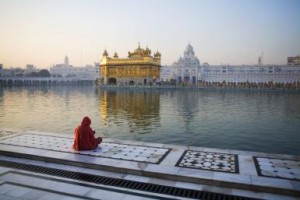 India, Amritsar, Golden Temple, Woman praying against temple